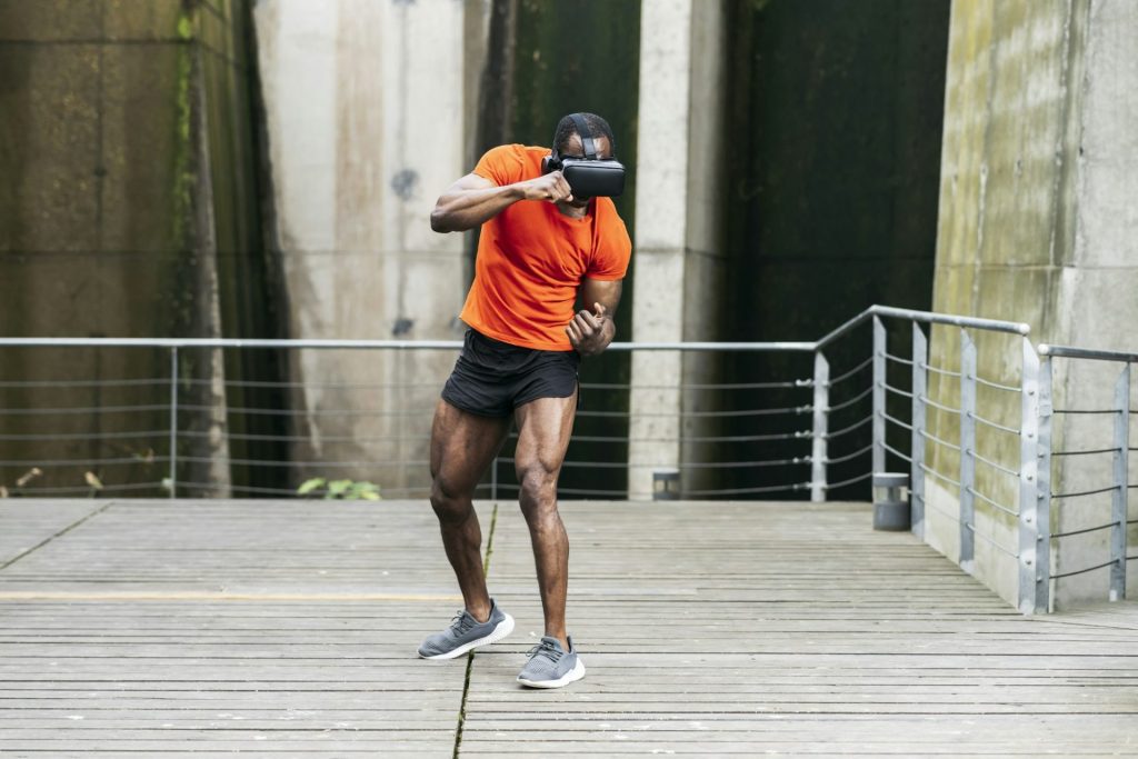 African american man training boxing punches with a virtual reality goggles in a park