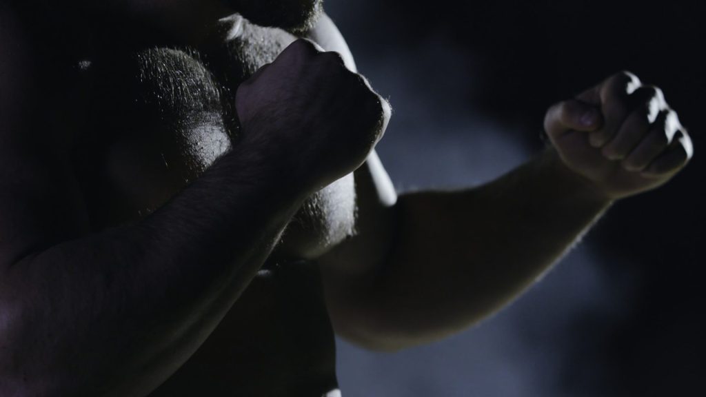 Boxing man ready to fight. Boxer with strong hands and clenched fists on a black background. Close