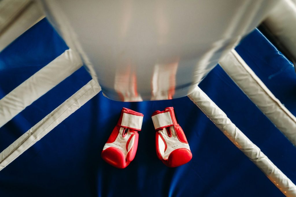 Close-up of red boxing gloves on the floor of a blue boxing ring