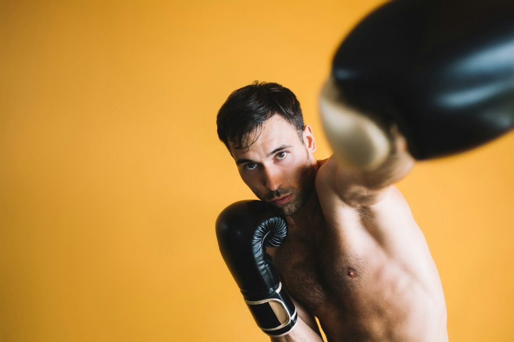 Strong man practicing in boxing gloves in gym